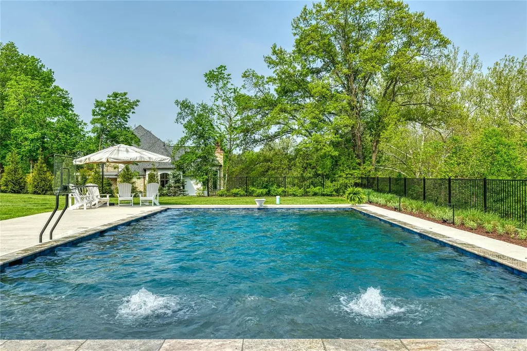 23 Brookwood Road Home in Saint Louis, Missouri. This remarkable residence showcases a grand two-story foyer, a library-paneled study, an elegant dining room, and a stunning great room with Palladian windows and a wet bar. The designer kitchen boasts quartzite countertops and commercial-grade appliances, while the master bedroom suite offers a marble bath and a private deck. 