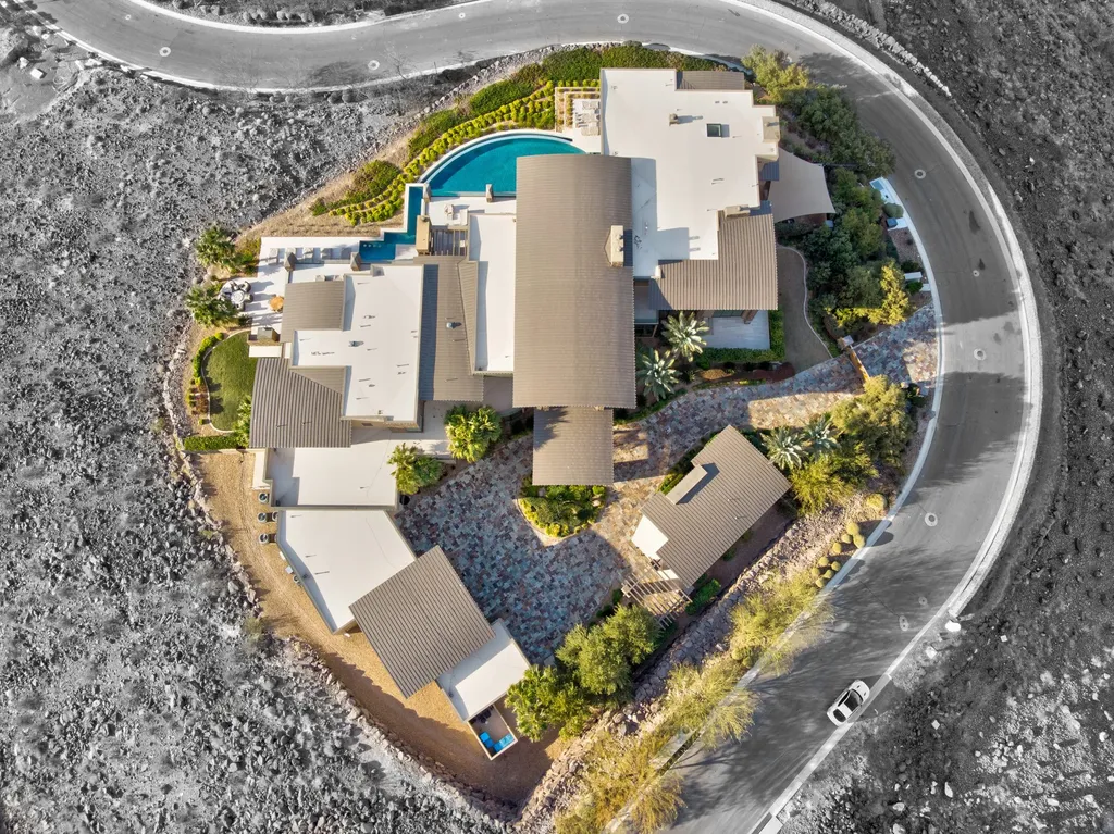 This extraordinary estate located at 761 Dragon Ridge Drive in Henderson, NV offers an unparalleled level of luxury and sophistication. Situated within the exclusive 9-lot enclave in Macdonald Highlands, this magnificent residence is nestled on a sprawling 1.23-acre lot, providing ample space and privacy.