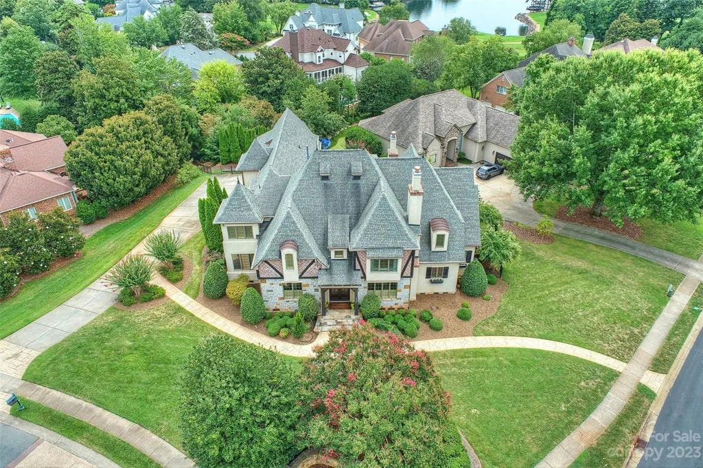 18726 John Connor Road Home in Cornelius, North Carolina. Discover a French-Tudor masterpiece where classic elegance harmoniously merges with contemporary comfort. This estate presents an enchanting façade with steep roofs, tall windows, and intricate wrought iron accents that embody ageless allure.