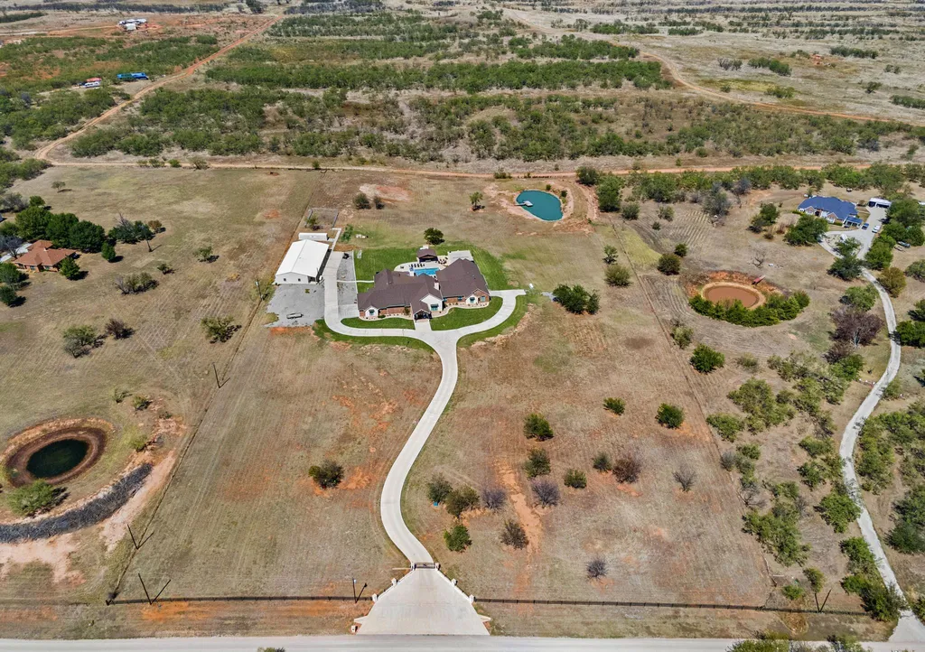 1134 Kinta Trial Home in Wichita Falls, Texas. Discover this unique 10-acre property in Clay County, featuring a stunning 6-bedroom home with 6.5 bathrooms, 6 fireplaces, a heated pool, outdoor kitchen, and even a catfish pond for fishing.