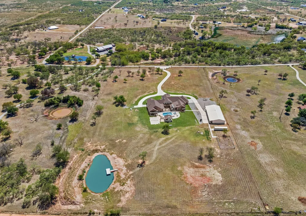 1134 Kinta Trial Home in Wichita Falls, Texas. Discover this unique 10-acre property in Clay County, featuring a stunning 6-bedroom home with 6.5 bathrooms, 6 fireplaces, a heated pool, outdoor kitchen, and even a catfish pond for fishing.