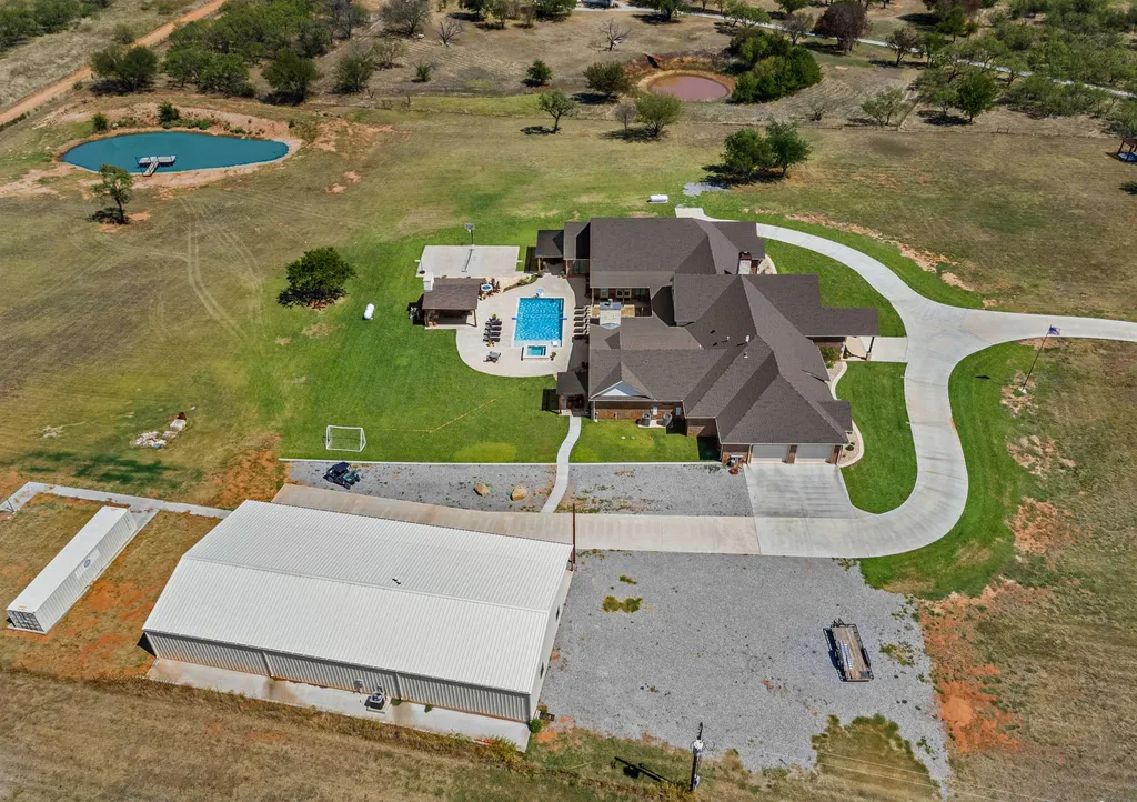 1134 Kinta Trial Home in Wichita Falls, Texas. Discover this unique 10-acre property in Clay County, featuring a stunning 6-bedroom home with 6.5 bathrooms, 6 fireplaces, a heated pool, outdoor kitchen, and even a catfish pond for fishing.