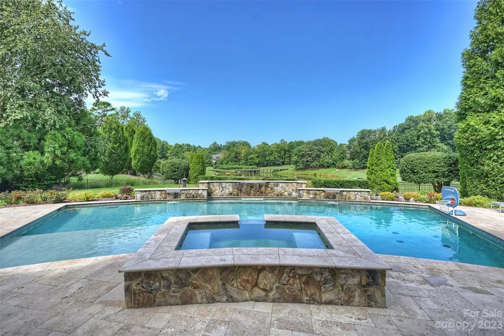 11717 Smart Lane Home in Charlotte, North Carolina. Experience the epitome of modern elegance in this gated estate with breathtaking views of the signature 13th hole from nearly every room and the stunning 48-ft pool. Designed by Christopher Phelps and crafted by Simonini, this home boasts an open floor plan, tall windows, curved walls, and a sweeping custom staircase inspired by Art Deco design.