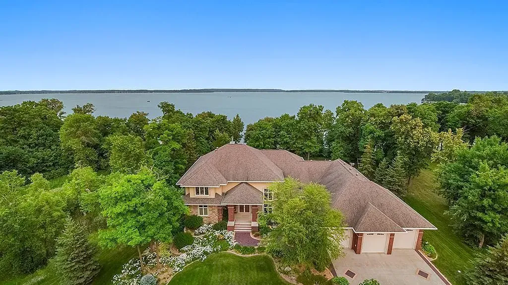 This stunning lakefront home is located in Cormorant Park Place, a premier lakeshore community. It has 6 bedrooms, 5 bathrooms, and 9,595 square feet of living space. The home features soaring ceilings, grand windows, hand-hewn imported wood, and hand-picked stone surfaces. It also has a private terrace with a fire pit, and access to the community's amenities, including a clubhouse, heated pool, swim beach, and slip system.