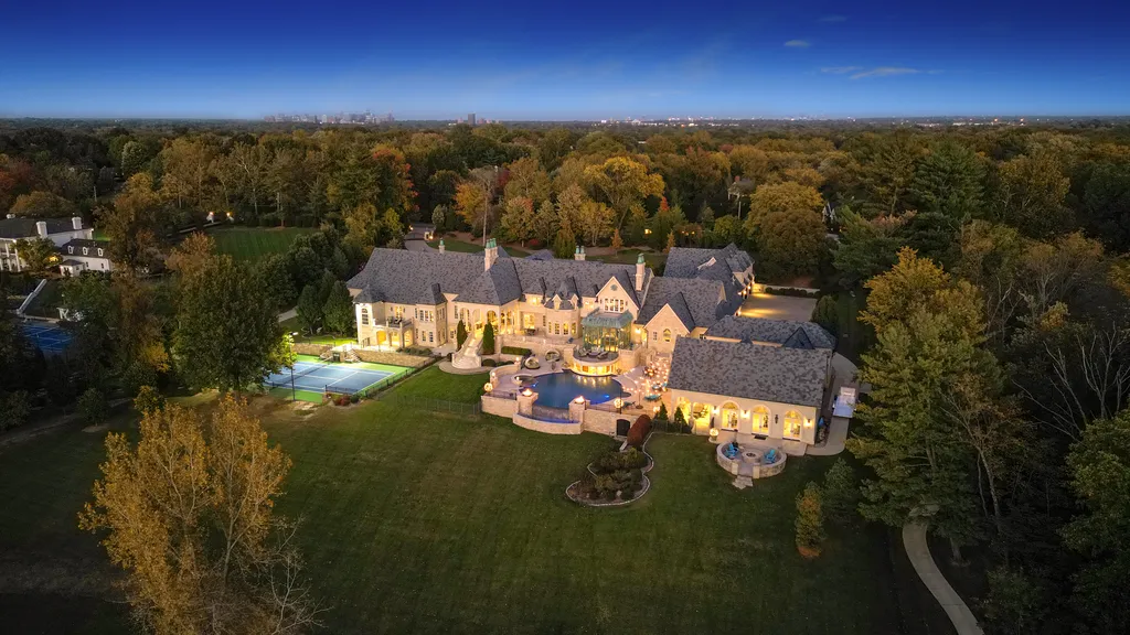 1705 North Woodlawn Avenue Home in Saint Louis, Missouri. Nestled on 7.5 acres of picturesque landscape with captivating tree-lined views, this French-inspired estate is a true masterpiece that harmonizes effortlessly with its serene surroundings. The property boasts an impressive ensemble of architectural wonders, including the main residence, a luxurious pool complex, a private lake, guest housing, and grand auto courts.