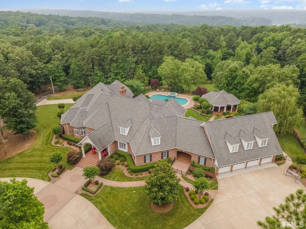 7728 Grace Cove Lane Home in Wake Forest, North Carolina. Discover this sprawling 31-acre estate featuring an exquisite all-brick home with custom features throughout. From reclaimed hardwoods to radiant heat flooring, this property exudes luxury. 