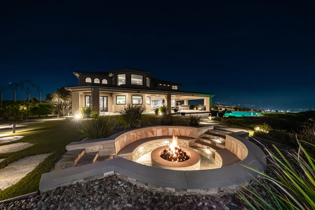 1045 Aquino Circle Home in Corona, California. Perched atop a private hill on over 4 acres, this 4,900 sqft custom home offers unparalleled views. Featuring 4 bedrooms, an office/bonus room, and a host of amenities, it was fully remodeled in 2016. Enjoy the remodeled interior, custom outdoor pool, spa, and entertainment area, RV hookup, detached 4-car garage with shop, A/C, and underground bunker.