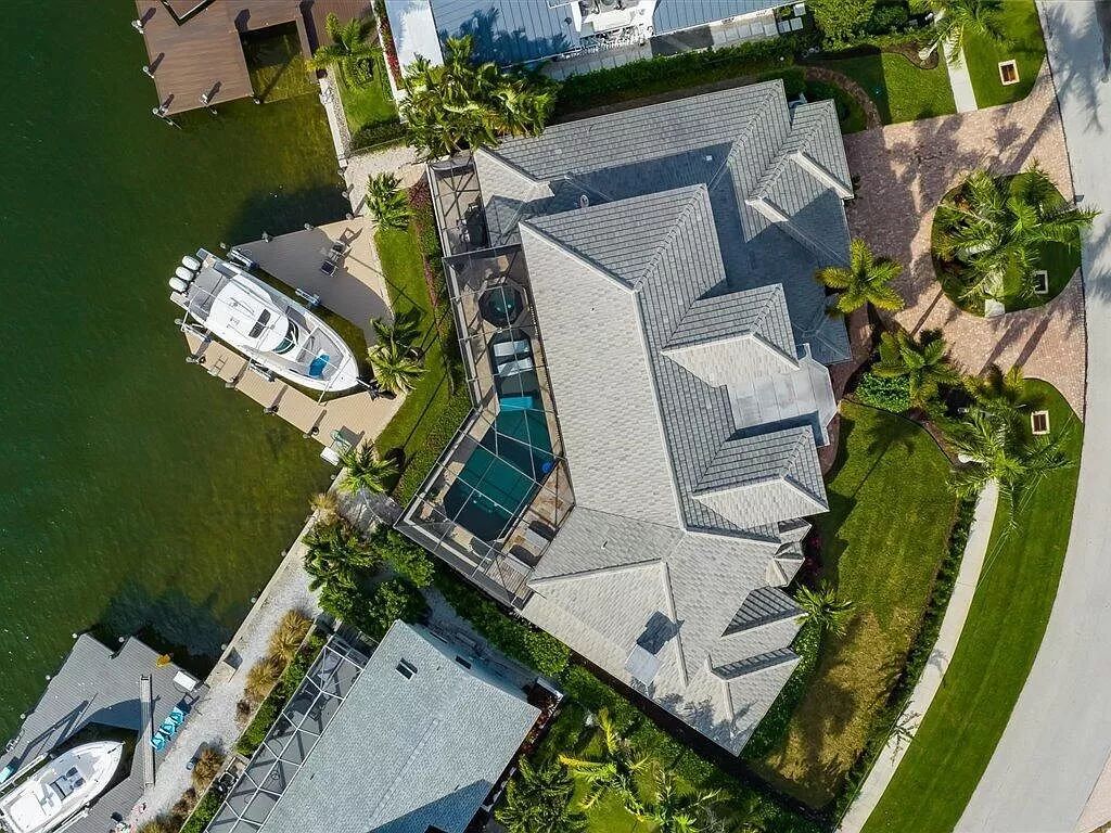 Indulge in waterfront luxury at 689 Rockport Ct, Marco Island, Florida - an architectural masterpiece marrying exquisite design and flawless construction. Sweeping southwest water views adorn nearly every corner of this timeless four-bedroom, six-bath residence boasting a theater room, home office, wine cellar, and a first-floor master suite with private pool access.