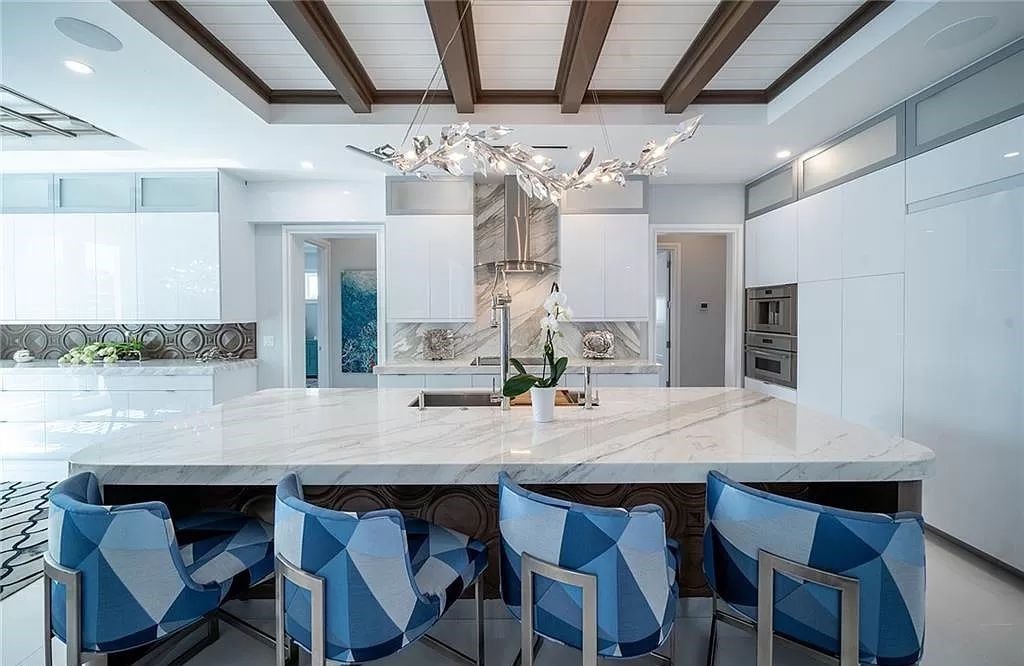 This five-bedroom, five-and-a-half-bathroom residence spans 5,298 square feet, boasting custom features and mesmerizing west-facing bay views. The grandeur of the home is evident in the soaring ceilings, book-matched marble fireplace, and a show-stopping dining room with a wine vault.