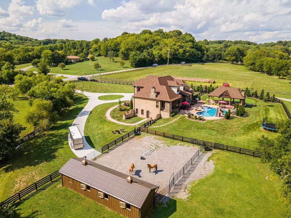 2214 Centerpoint Road Home in Hendersonville, Tennessee. Step into luxury with this European-style masterpiece by Hannah Custom Homes! Discover a gated 5-acre estate featuring a fully fenced equestrian farm, a 3-stall barn with tack room and electricity, cross-fencing with 7 gates, and an outdoor living dream with a lagoon-shaped heated pool, multiple covered porches, pool pavilion, hot tub, and more. 