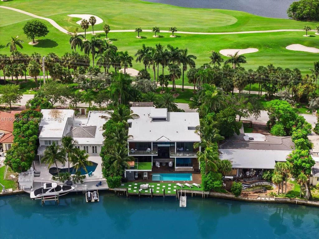 Nestled between the Biscayne Waterway and Miami Beach Golf Club, this 5-bed, 7-bath home offers breathtaking views, a lush outdoor oasis with terraces, a summer kitchen, pool, cabana bath, and rooftop hot tub.