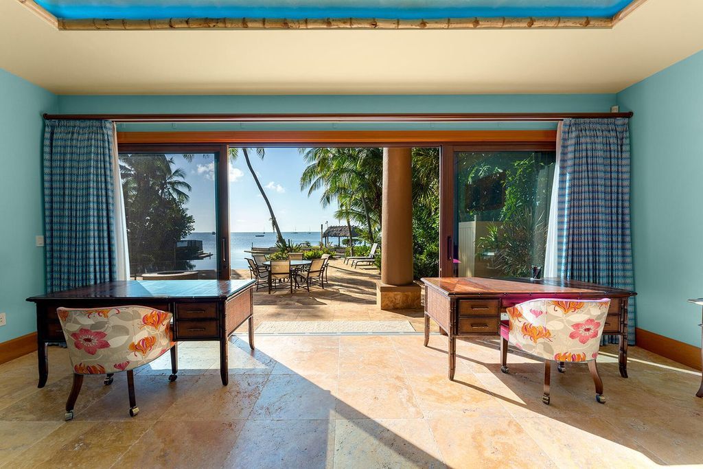 This exquisite bayfront property features a main home with four bedrooms, four full bathrooms, and two half bathrooms, plus a guest house with two bedrooms and one bathroom.