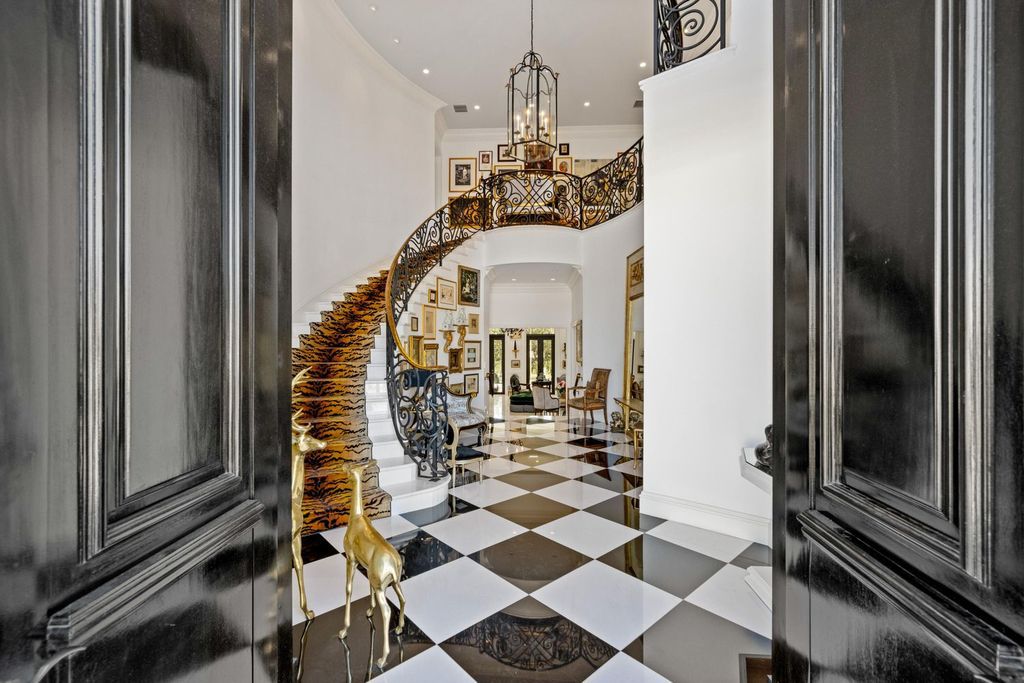 This 6-bedroom, 6.5-bathroom masterpiece, inspired by classic European estates, boasts soaring ceilings, a sweeping staircase, and grand living spaces including formal living and dining rooms, a den, and a separate bar.