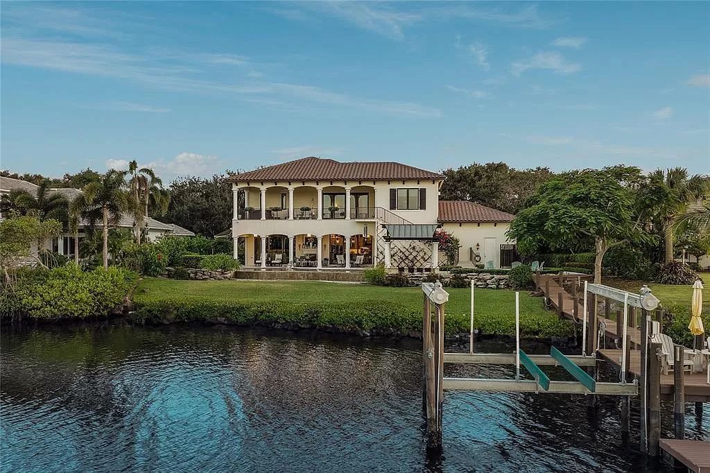 Located on a picturesque, tree-lined street, this Mediterranean-inspired custom waterfront home by P B Built is a true gem.