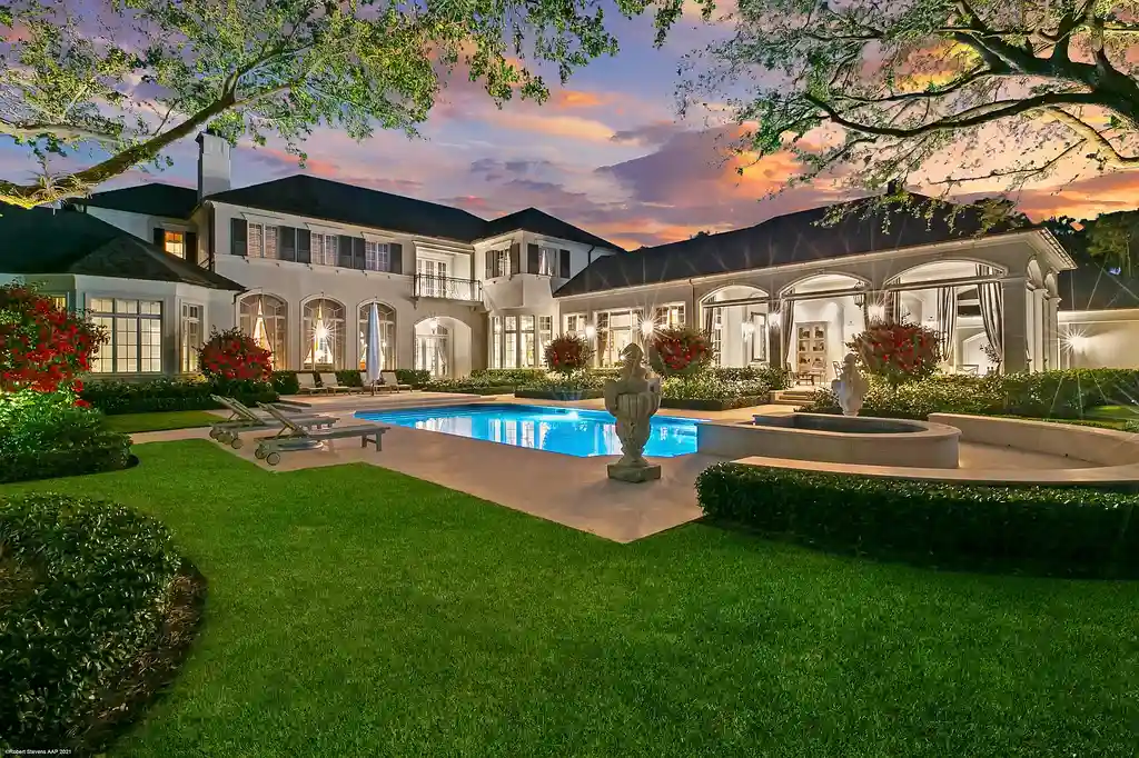 Aerial view of the exquisite French Country estate at 146 Bears Club Drive in Jupiter, FL, showcasing lush manicured grounds, a scenic residential lake, and panoramic golf course views.