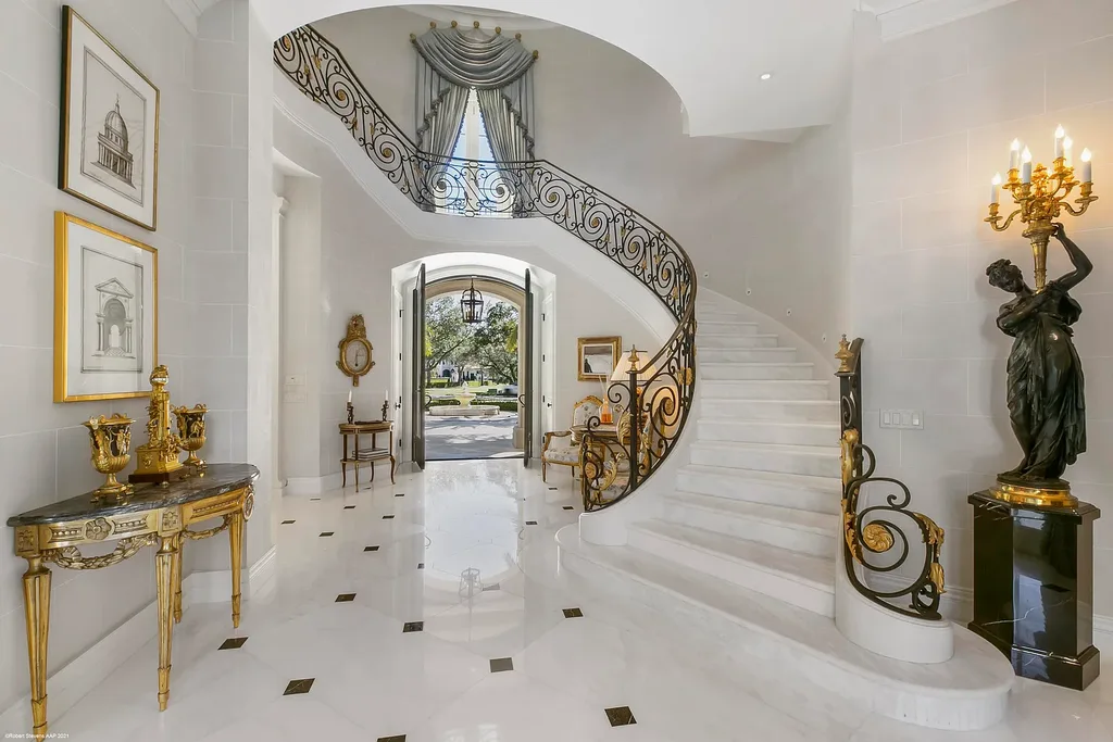 Aerial view of the exquisite French Country estate at 146 Bears Club Drive in Jupiter, FL, showcasing lush manicured grounds, a scenic residential lake, and panoramic golf course views.