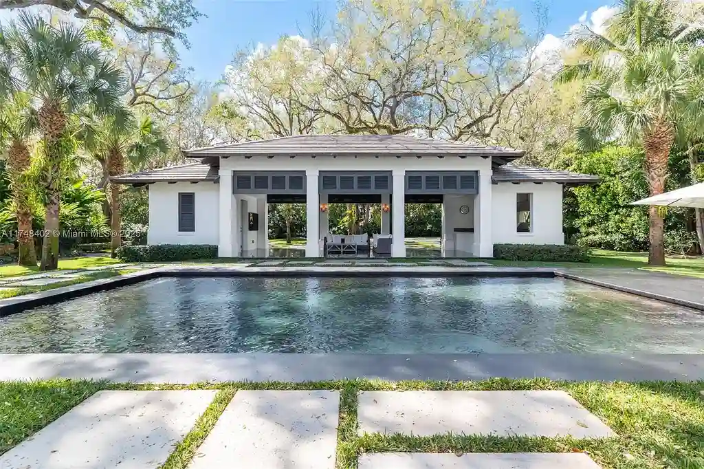 A luxurious $14.97M estate at 8150 SW 52nd Ave, Miami, featuring a heated saltwater pool, gourmet kitchen with Calacatta marble island, and lush landscaped gardens in the exclusive Ponce-Davis neighborhood.