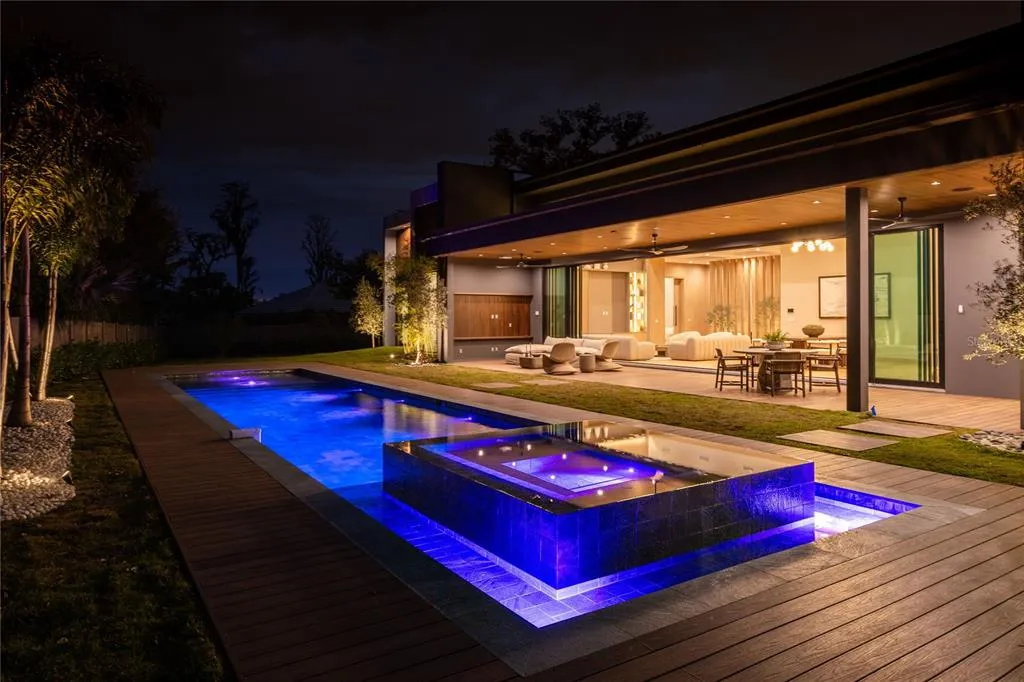 Expansive 65-foot pool at 8968 Bay Cove Ct in Orlando, surrounded by Amazon green limestone tiles and a fully equipped summer kitchen.