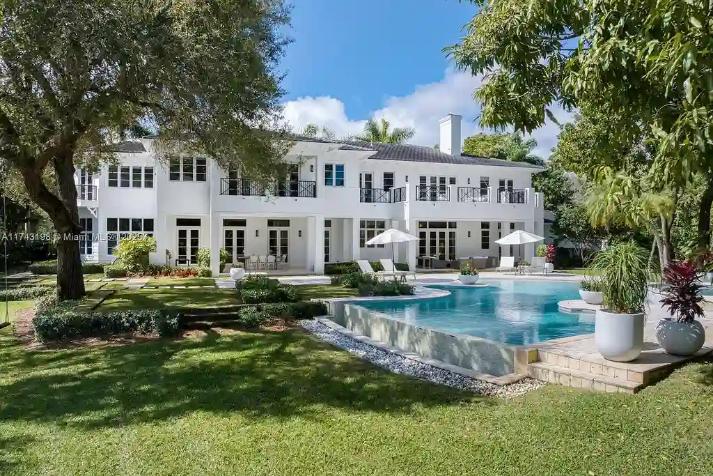 Breathtaking backyard at 9001 Banyan Dr, Coral Gables, featuring an infinity-edge pool, a spacious terrace, and panoramic views of Hammock Lake.