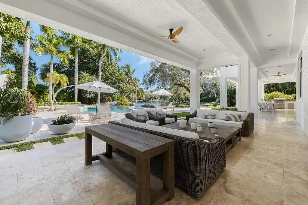 Breathtaking backyard at 9001 Banyan Dr, Coral Gables, featuring an infinity-edge pool, a spacious terrace, and panoramic views of Hammock Lake.