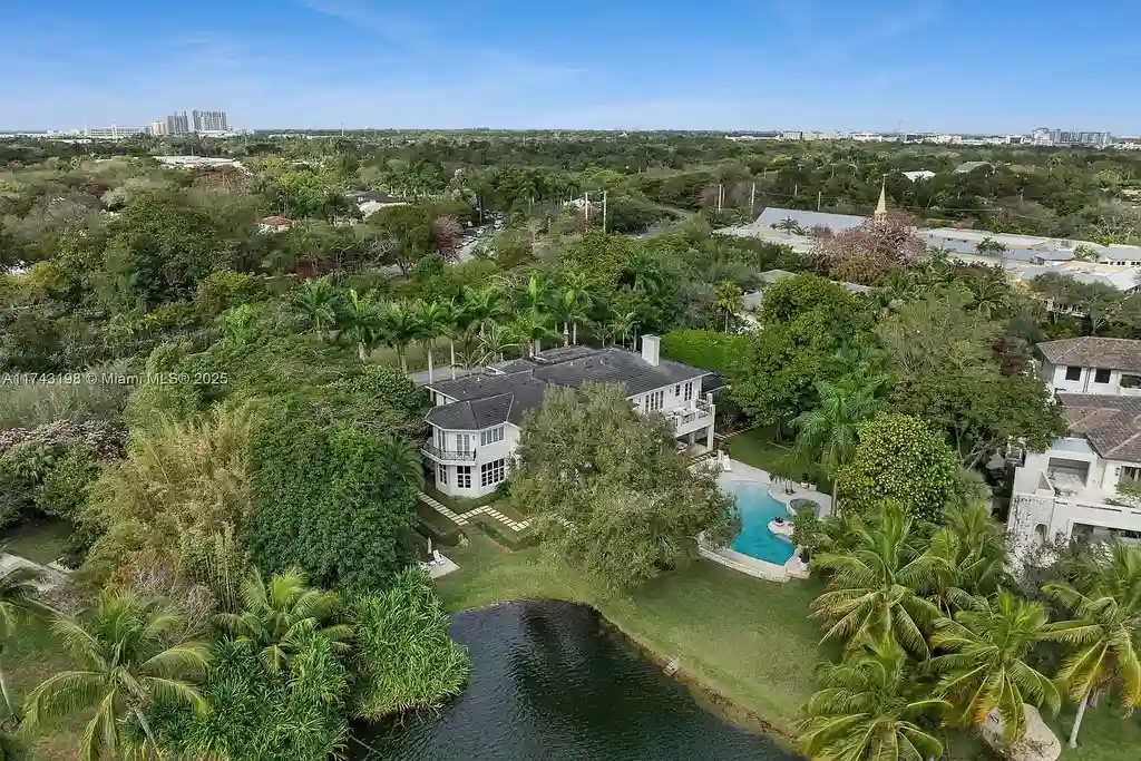 Breathtaking backyard at 9001 Banyan Dr, Coral Gables, featuring an infinity-edge pool, a spacious terrace, and panoramic views of Hammock Lake.