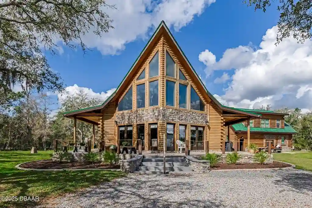 Stunning log cabin estate at 1100 Tallacoe Trl, New Smyrna Beach – a $3.8M rustic retreat with wrap-around porch and expansive countryside views.