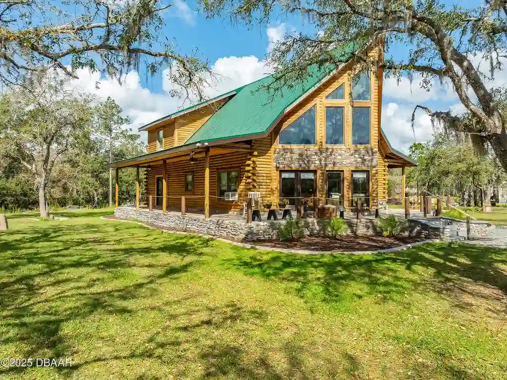 Stunning log cabin estate at 1100 Tallacoe Trl, New Smyrna Beach – a $3.8M rustic retreat with wrap-around porch and expansive countryside views.