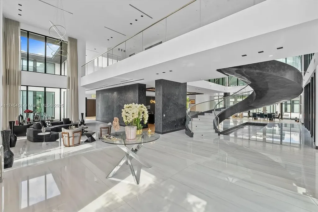 Spacious open-plan living room in 6555 SW 102nd St, featuring double-height ceilings, elegant marble floors, and floor-to-ceiling windows with natural light.