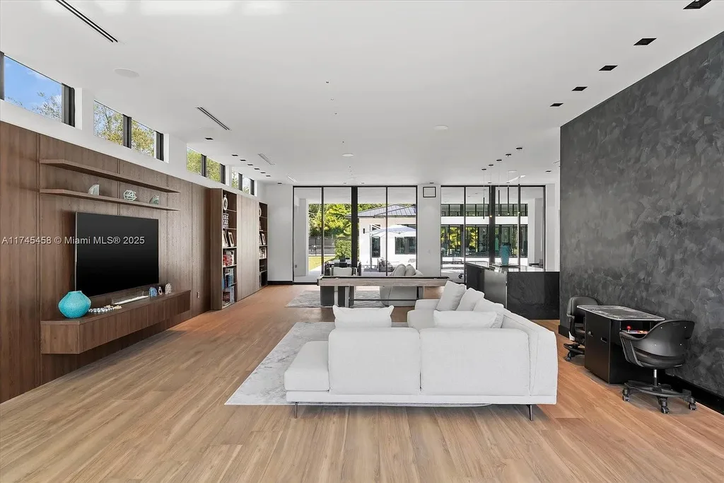 Spacious open-plan living room in 6555 SW 102nd St, featuring double-height ceilings, elegant marble floors, and floor-to-ceiling windows with natural light.