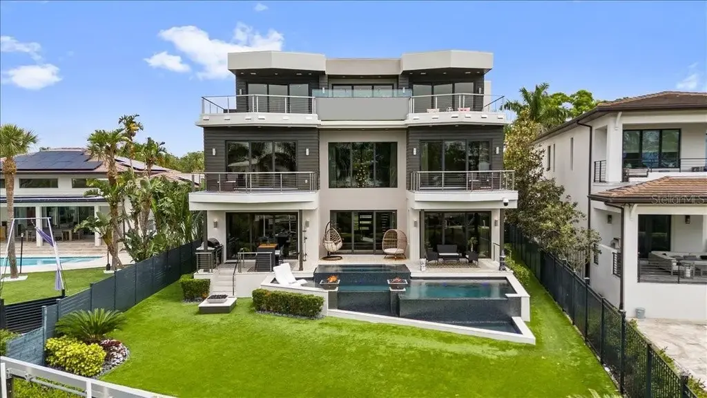 Luxury waterfront estate at 5131 W Neptune Way, Tampa featuring modern architecture, private dock, saltwater pool, rooftop terrace, and smart home technology