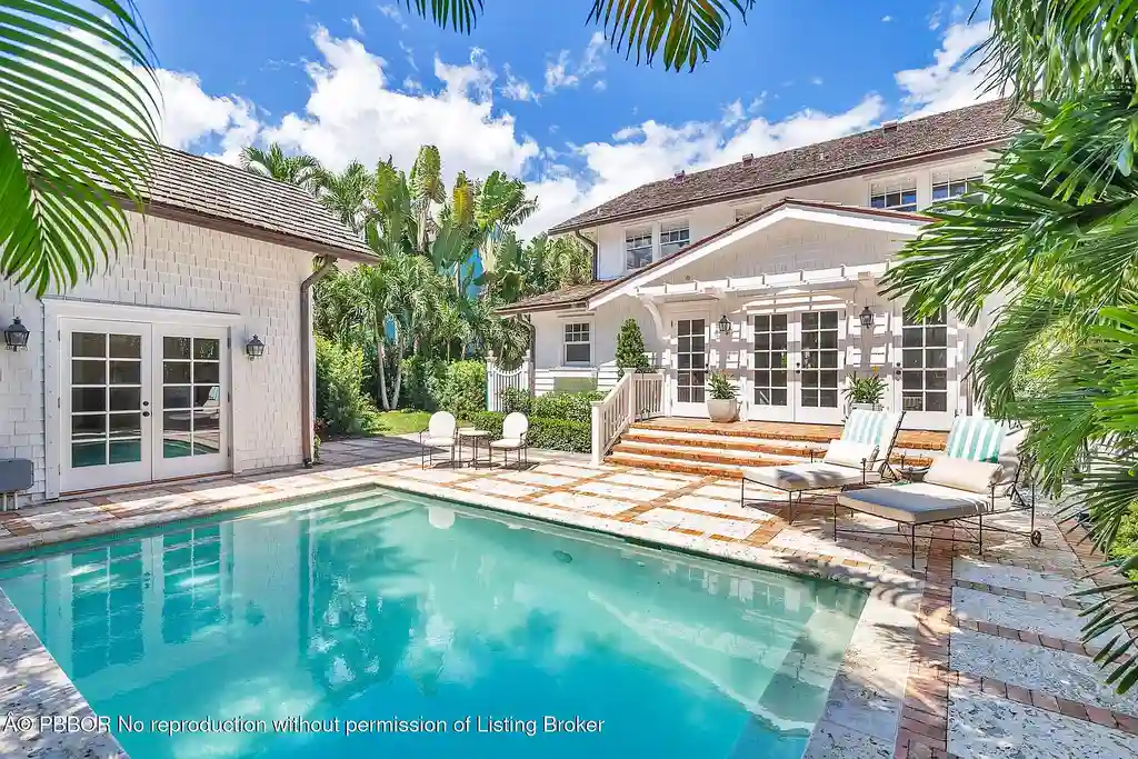 Elegant front view of the renovated $13.5M bungalow-style home at 142 Seabreeze Ave, Palm Beach, featuring guesthouse, heated pool, and lush landscaping