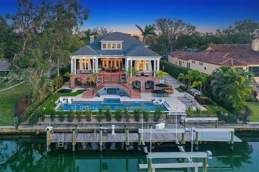 Elegant Georgian colonial waterfront estate at 1541 Bay Point Dr in Sarasota, FL featuring private dock, saltwater pool, theater room, and lush tropical landscaping.