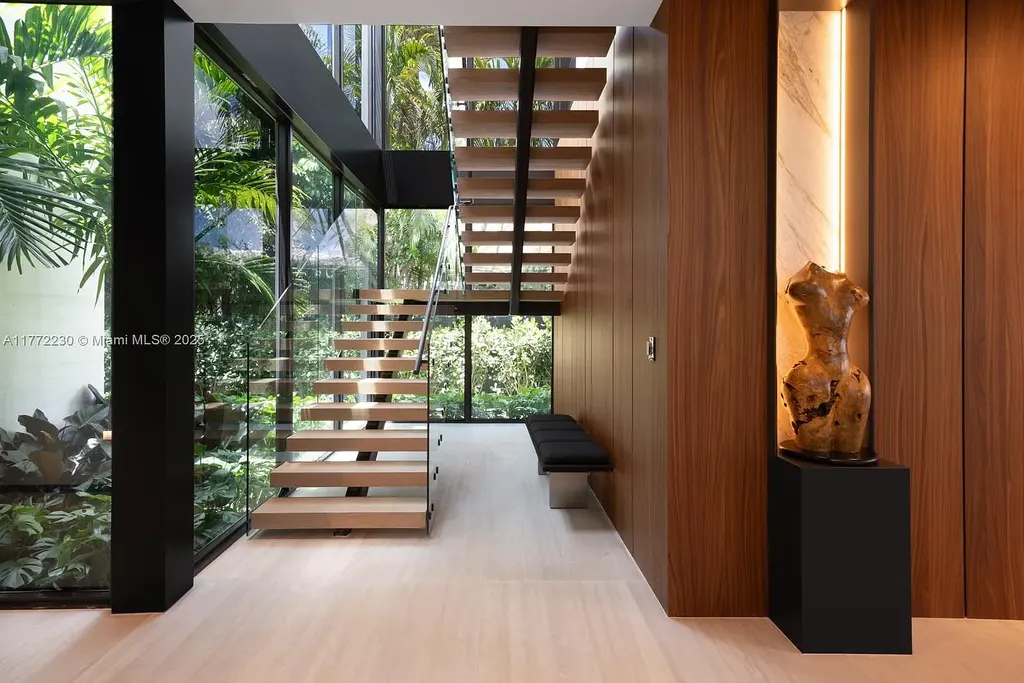 Spacious living room featuring Minotti furnishings, floating staircase, and soaring ceilings in luxury Miami Beach home for sale