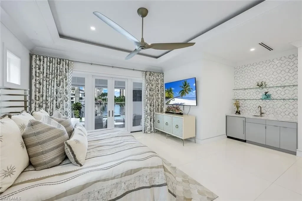 Infinity-edge saltwater pool and private dock at luxury home in Naples for sale, located on Venetian Bay with waterfront views.