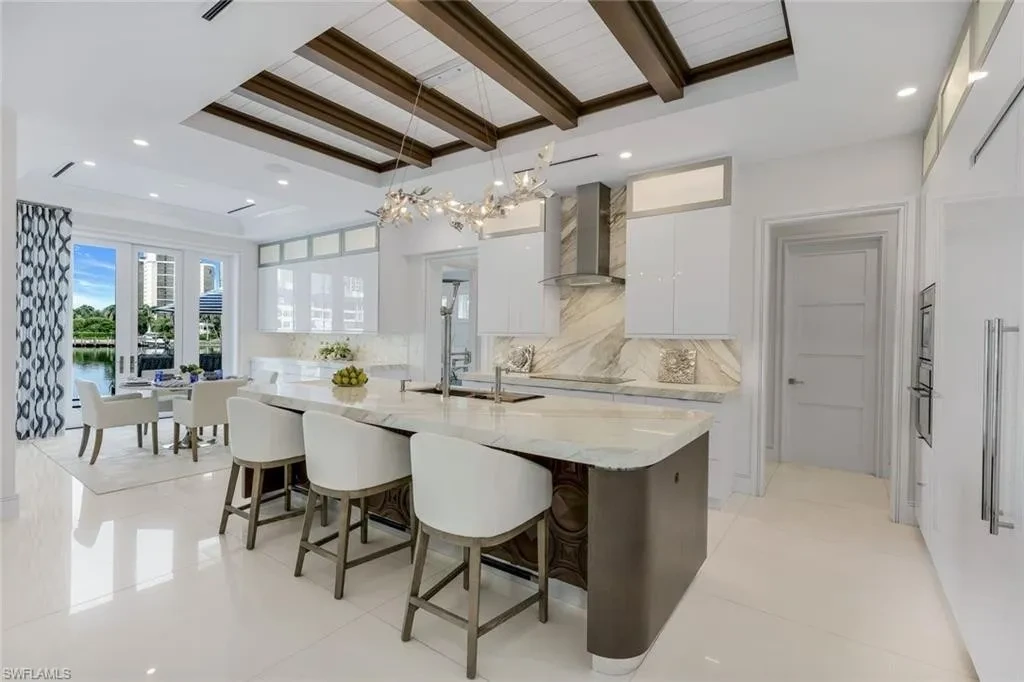 Infinity-edge saltwater pool and private dock at luxury home in Naples for sale, located on Venetian Bay with waterfront views.