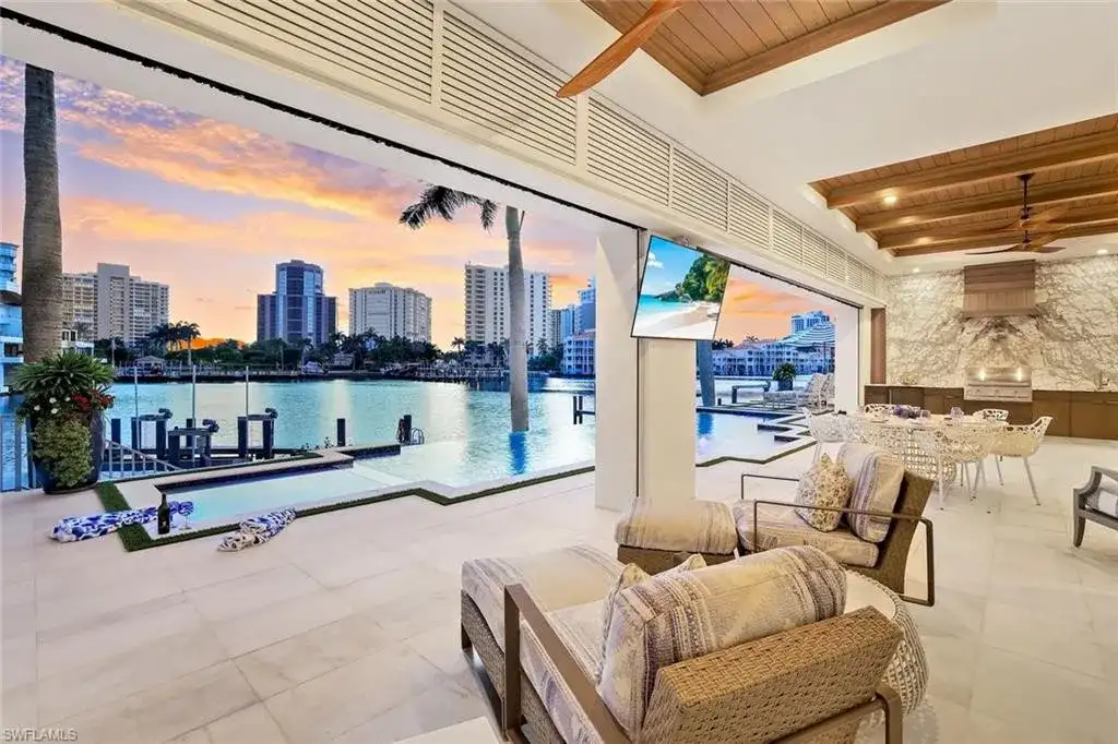 Infinity-edge saltwater pool and private dock at luxury home in Naples for sale, located on Venetian Bay with waterfront views.