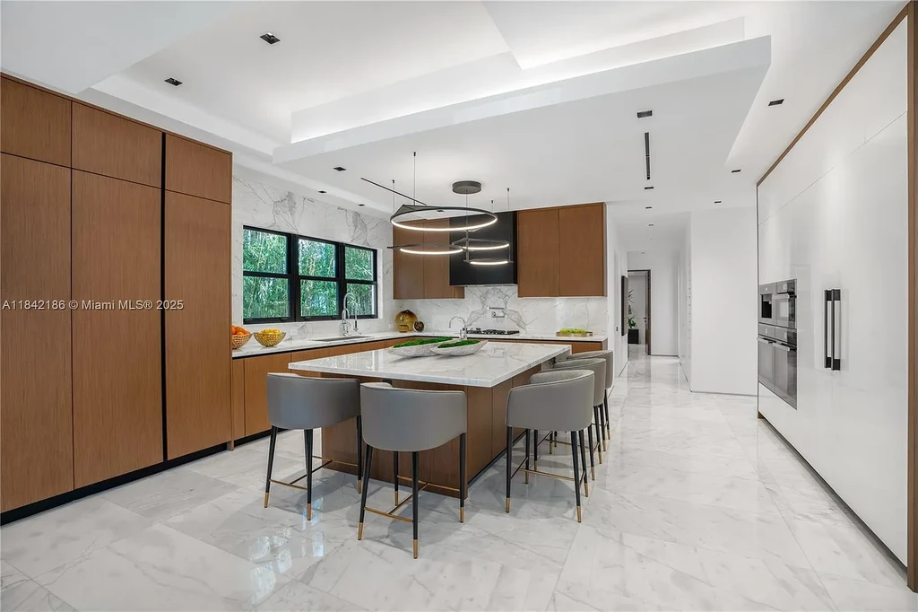 Luxurious waterfront home at 4241 Palm Ln in Miami featuring private dock, infinity-edge pool, modern tropical architecture, and lush Ipe wood deck