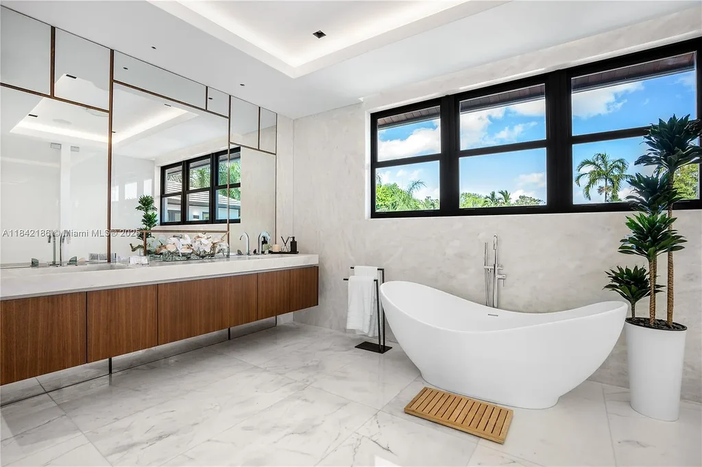 Luxurious waterfront home at 4241 Palm Ln in Miami featuring private dock, infinity-edge pool, modern tropical architecture, and lush Ipe wood deck