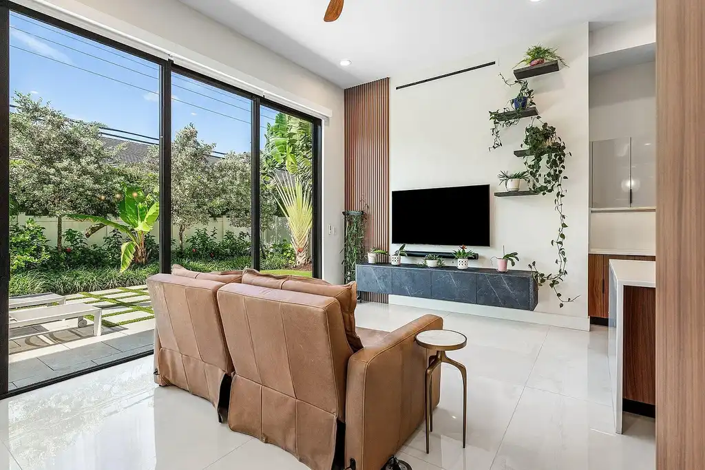 Modern living room inside 450 NE 10th Street featuring soaring ceilings, impact glass, and remote-control fireplace