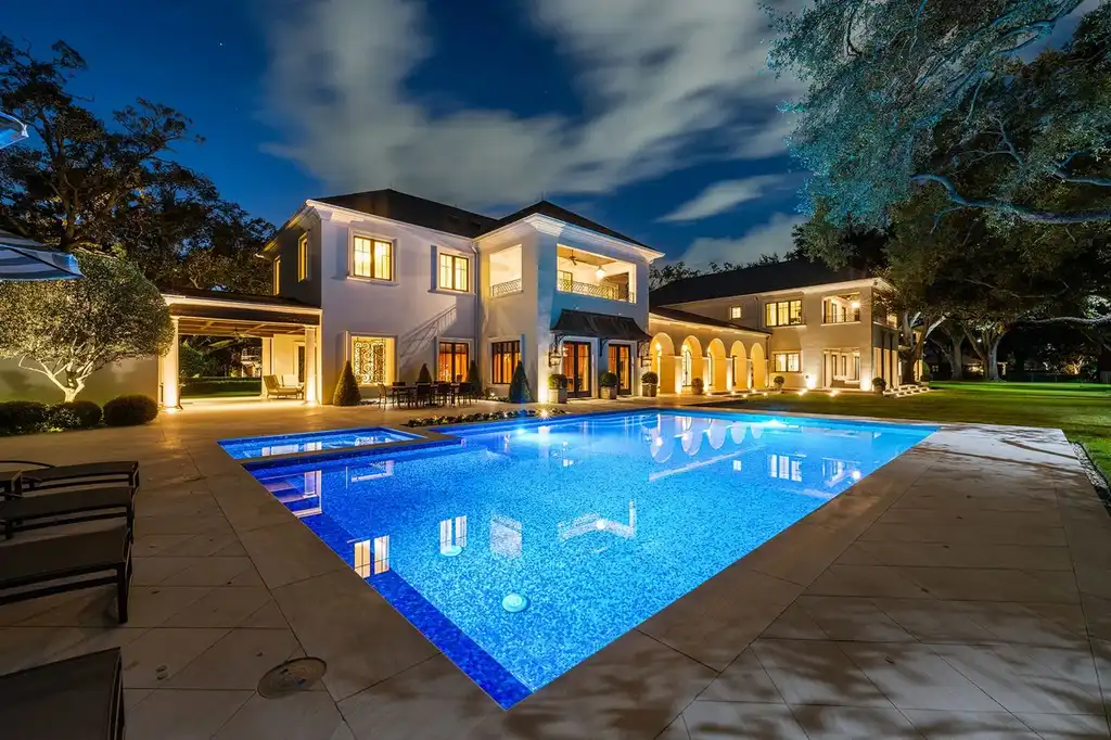 Outdoor living space with heated saltwater pool, cabana, and manicured gardens overlooking golf course